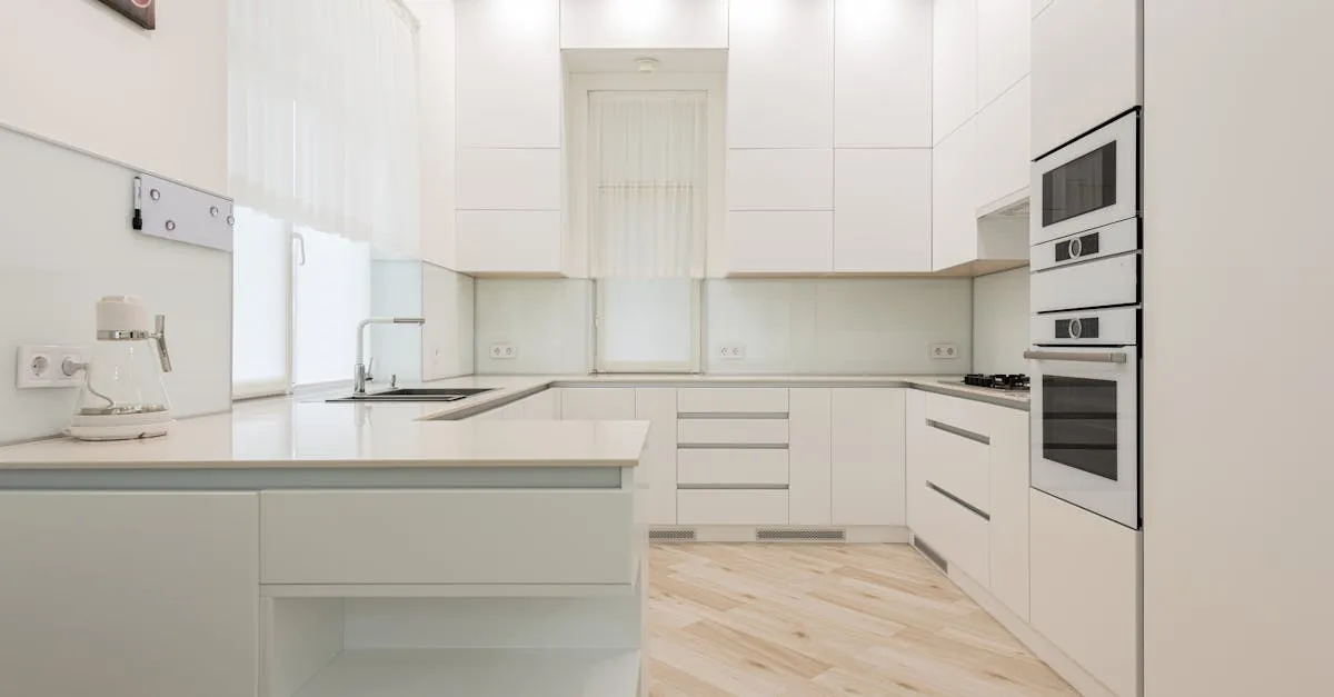Interior of light kitchen with white cabinets and kettle near sink placed against trendy oven and modern appliances in a