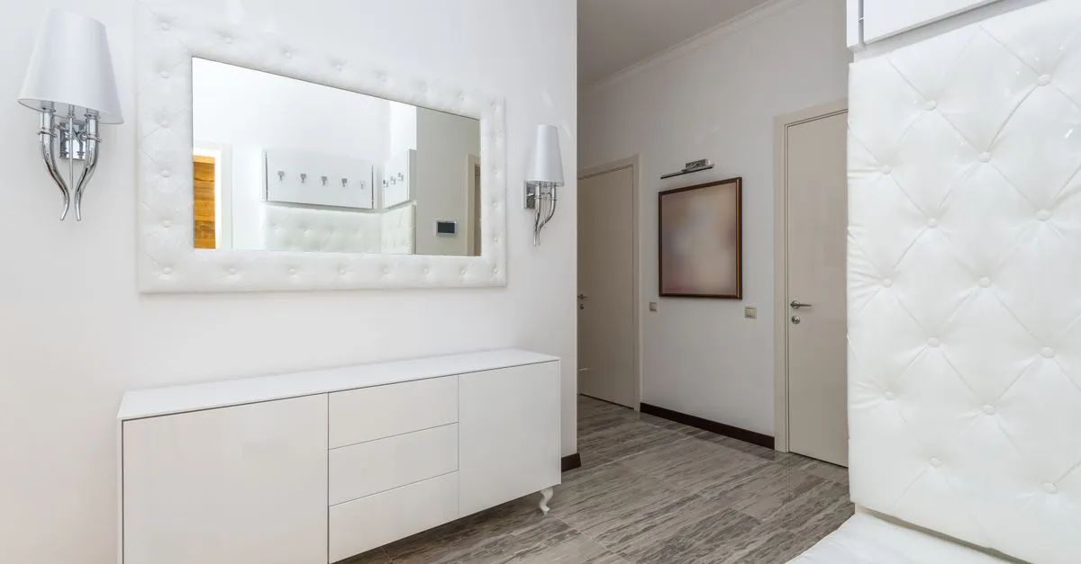 Stylish modern interior featuring white decor, a large wall mirror, and contemporary furnishings.