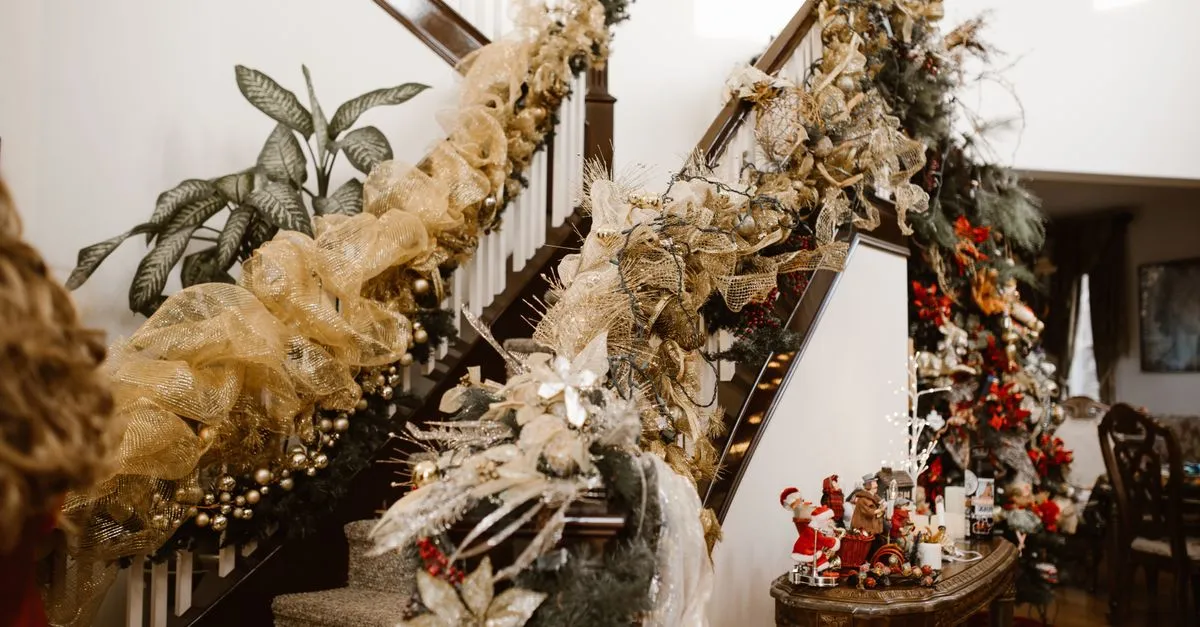 Luxurious gold and green Christmas decorations adorn an indoor staircase creating a festive atmosphere.